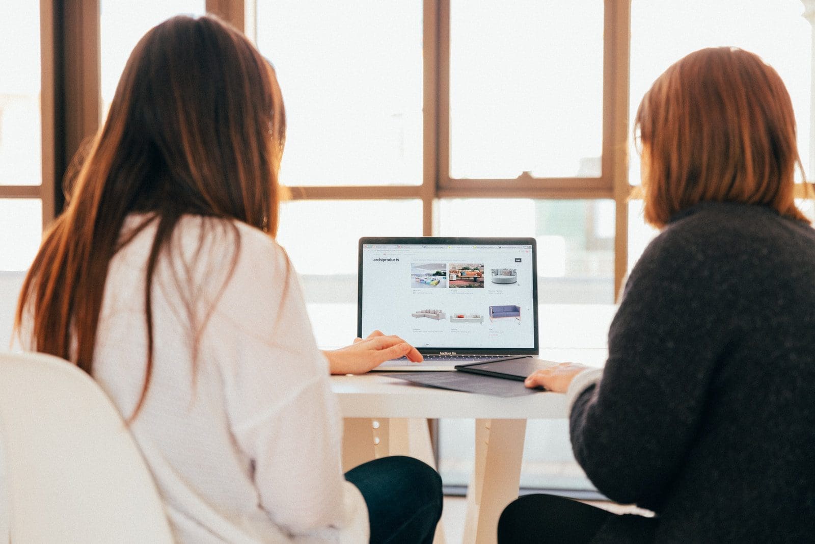 ecommerce marketing two women talking while looking at laptop computer