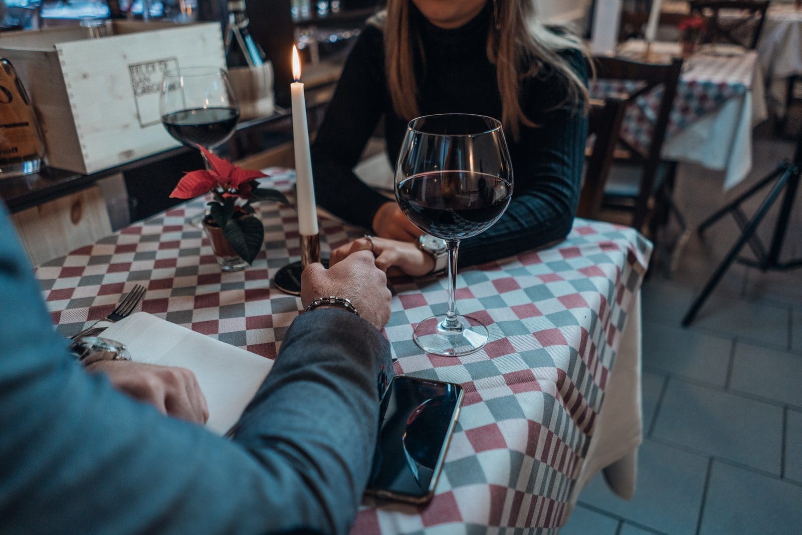 Dating woman wearing black sweater holding hand with man wearing gray suit jacket