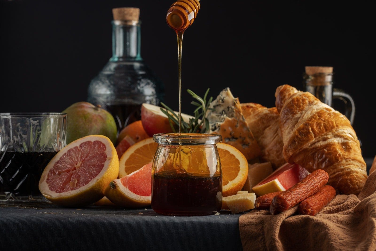 Sliced Orange Fruit Beside Clear Glass Jar with Honey