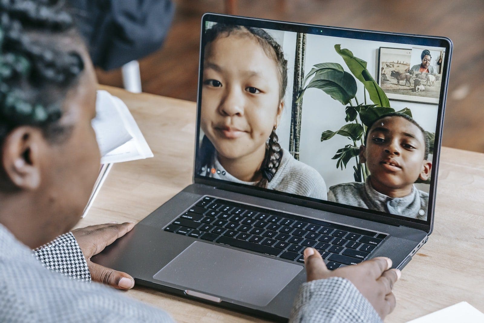Black woman working online with pupils on laptop