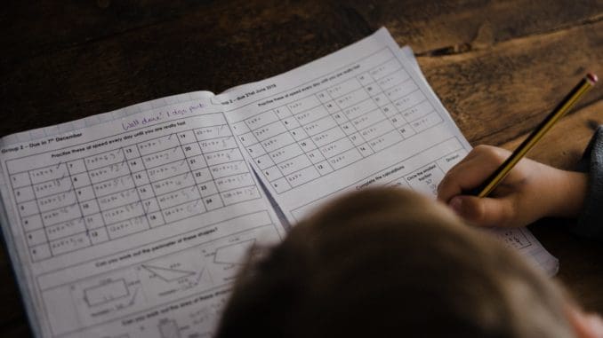 boy writes on his book on the desk