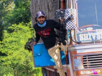 man in black long sleeve shirt and brown pants standing beside red truck during daytime
