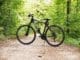 Black and White Hardtail Bike on Brown Road Between Trees select a bicycle