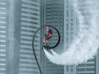 man in orange jacket riding bicycle on white water wave during daytime dubai with friends