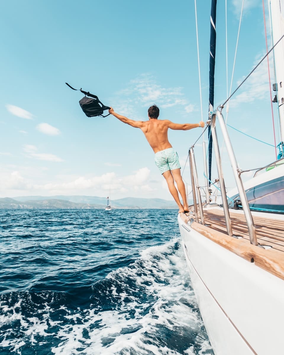 man wearing white shorts holding black backpack sailing vacation